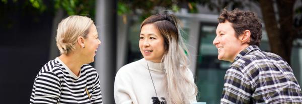 Three female UTS staff members talking and laughing.