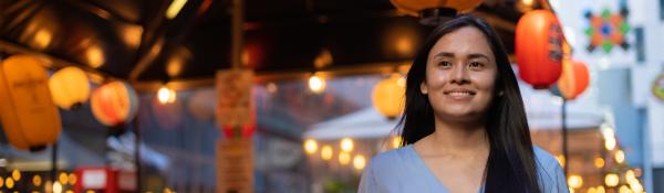 An international student walking in Darling Square with lanterns in the background