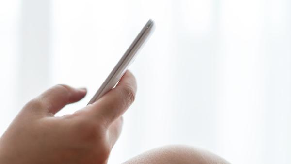 800x450 holding a mobile phone in front of the window with curtains