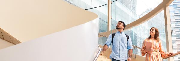 Two international students looking up whilst standing on a spiral staircase