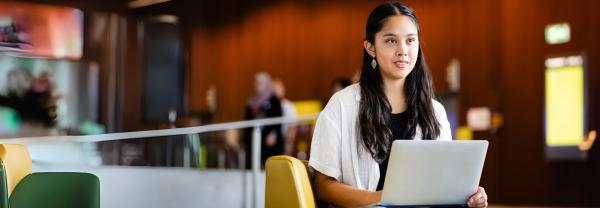 A student sitting with her computer in the foyer of UTS building 11