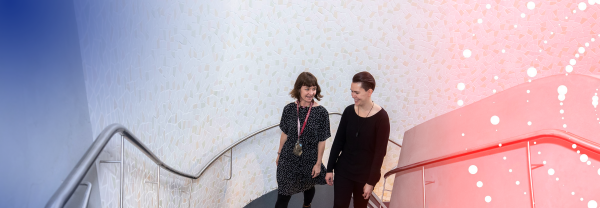 Two people walking up a staircase and engaging in casual conversation.