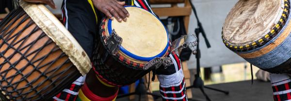 Closeup of three artist performing traditional colorful string wrapped african djembe drums while standing on stage during event