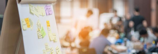 Flip chart with post it notes and people blurred in background