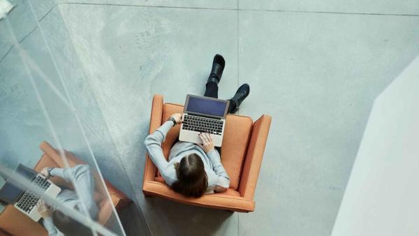 Overhead photo of a woman working on a laptop while sitting in a brown lounge chair