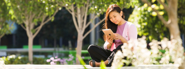 Woman sitting outside while looking at a smart device.