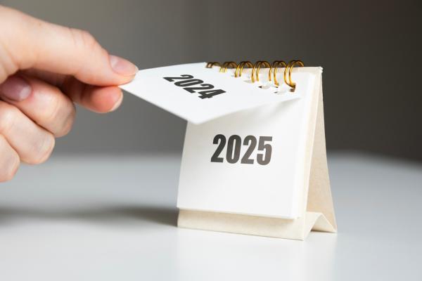 hand turns over a calendar sheet. year change from 2024 to 2025