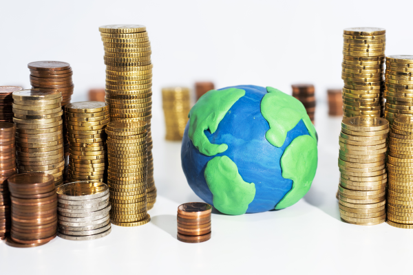 Stacked coins next to clay model of Earth.
