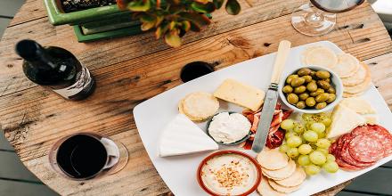 A cheese board and a bottle and glass of wine 