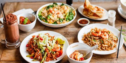 A wooden table of plates featuring Malaysian food 