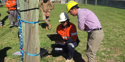 Man outdoors in hard hat using a laptop