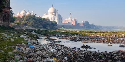 Indias contrast of ugly pollution and stunning beauty, The banks of Yamuna River polluted with garbage and beautiful Taj Mahal in the background