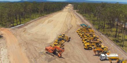 Maintenance vehicles on dirt road surrounded by bush