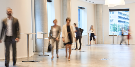 People walking through office building foyer.