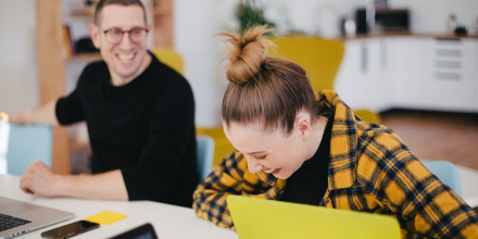 Two students at desk, laughing.