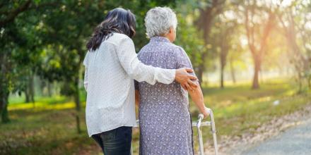 Woman helping elderly person walk outdoors