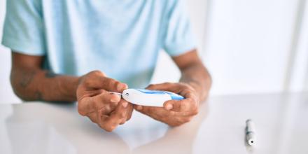 Man measuring glucose levels at home