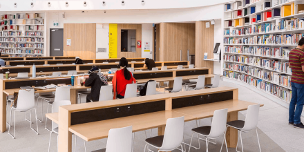 A wide angle shot of UTS Library showing rows of books with different colours and students studying