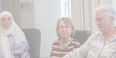 Three women sitting at a board room table.