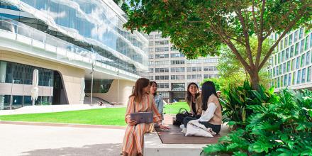 A group of UTS students sitting together and socialising in greenery backdrop