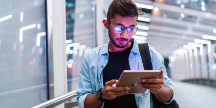 A student looking at his tablet with screen reflection on his glasses.