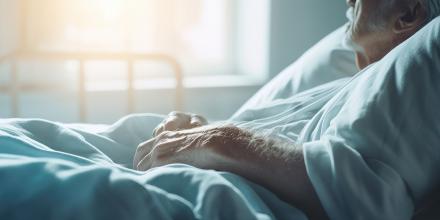An elderly man in a hospice bed looking out of the window in the distance