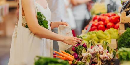  Female hands puts fruits and vegetables in cotton produce bag at food market