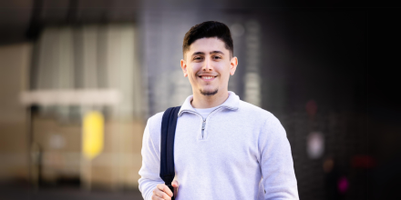 IT Student Oliver with a backpack over one shoulder. Building 11 at UTS is in the background