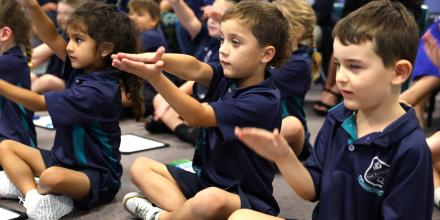 Children sitting down in a group, engaged in an activity.