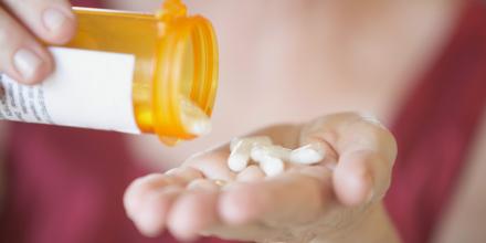 Closeup of woman pouring tablets out of a bottle and into her hand