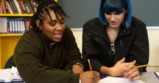 Two people sitting down and studying together