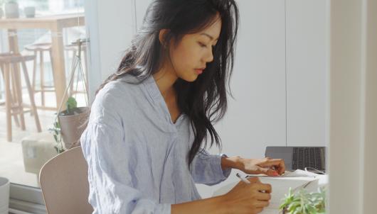 Rachel Tse designing at a table in a bright cafe