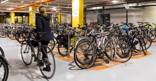 A person walking a bike into a room of bikes