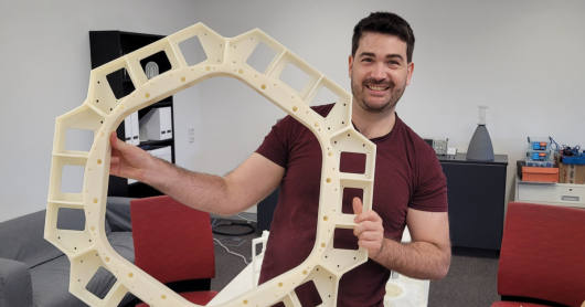 Clyde holding a full-scale prototype of the top plate of the Space Machines Company’s spacecraft upper bay