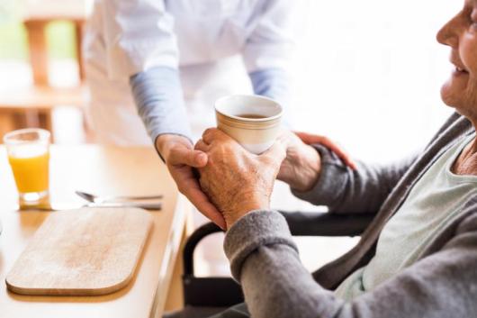 Elderly woman in aged care is assisted by a nurse