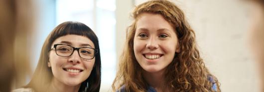Two women talking to blurred people in the foreground