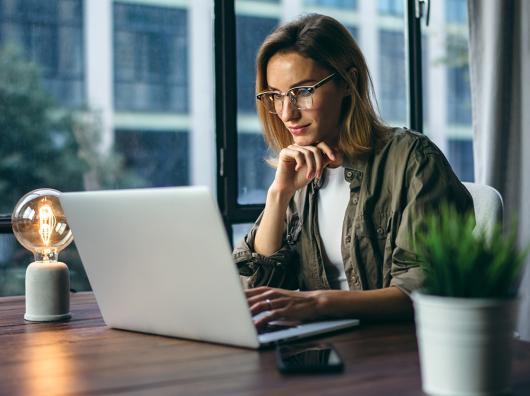 A woman looks pensively at her computer.