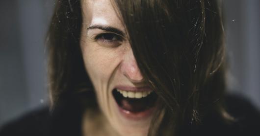 A woman screams while looking down barrel of the camera.