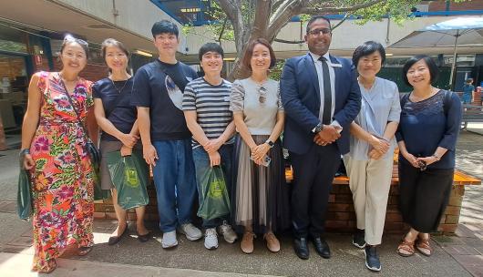 outdoor group photo of people academics and students standing side by side and smiling under a tree