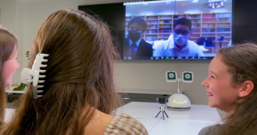 A group of children speak with students via Zoom with Haru the Social Robot facilitating the conversation.