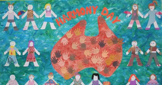 A child's artwork with paper dolls holding hands across Australia and hand prints of various colours with the words 'Harmony Day' across the top.