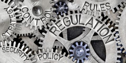 A picture of cogs in black and white. Each cogs represents a word, such as 'regulation', 'security', 'rules', 'strategy'. 