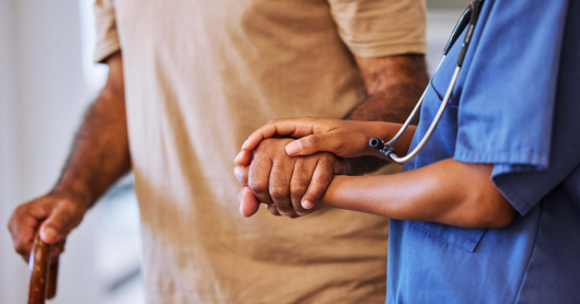 A nurse assisting an elderly man walk