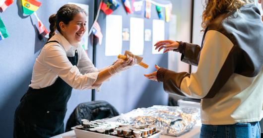 Churros being handed across a table of food