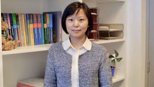 Professor Ling Chen medium shot standing in front of a book shelf.