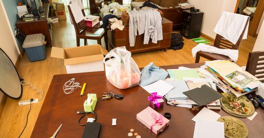 a living room with papers, clothes and objects in disarray