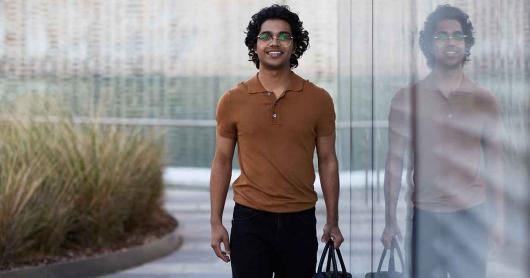 Young man carrying a briefcase walks along the balcony of the University of Sydney Library