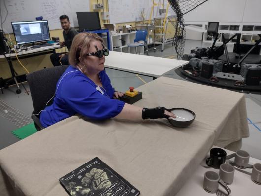 A research team member who is blind uses acoustic touch to locate and reach for an item on the table.  Photo: Lil Deverell CC-BY 4.0 