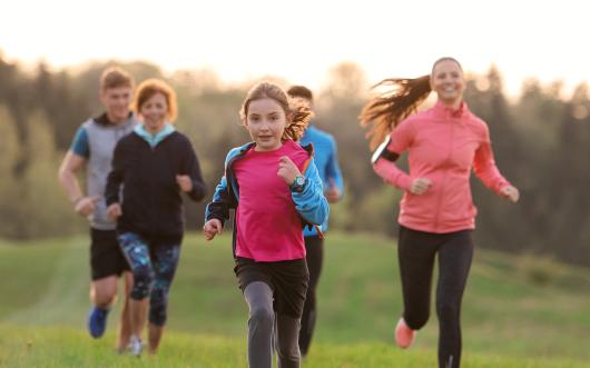 Stock picture of a group of adults and children exercising outdoors