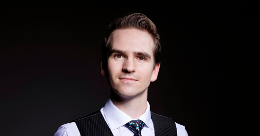 Well-groomed young man with dark hair in business attire looking at camera